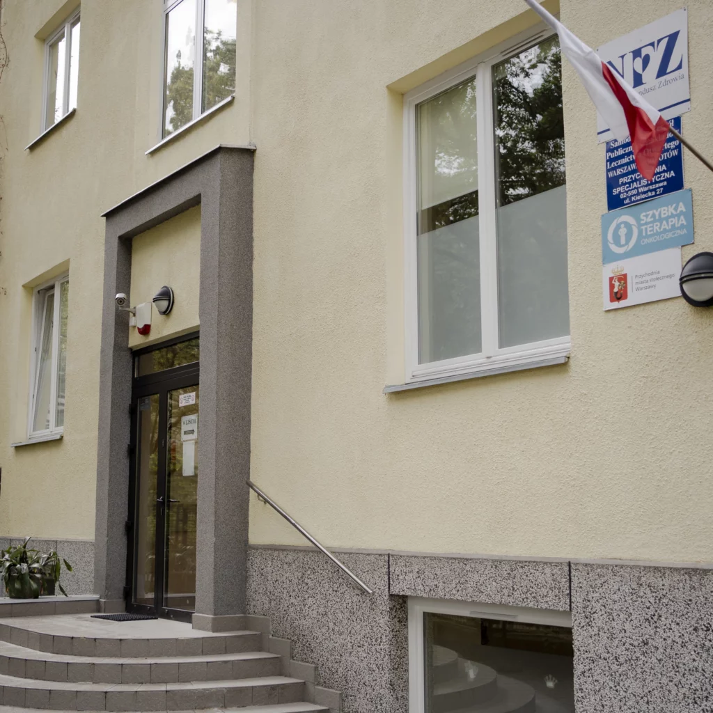 Wejście do budynku przychodni z tablicą NFZ i flagą Polski