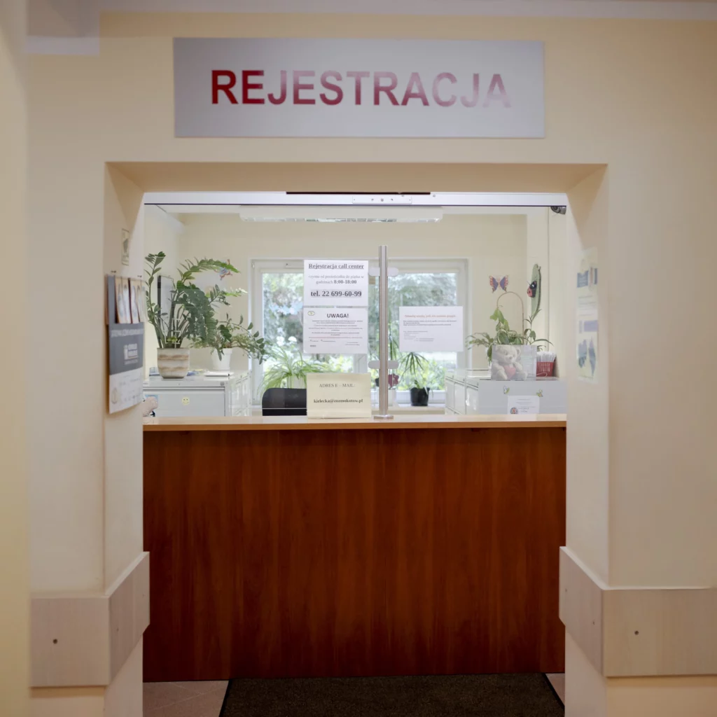 Rejestracja w przychodni z okienkiem obsługi i roślinami na parapecie