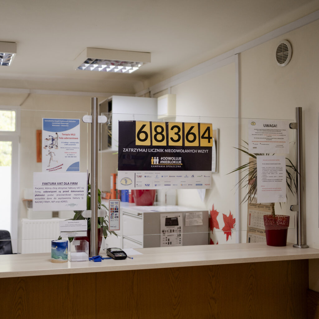 Rejestracja przychodni z plakatem kampanii przypominającej o odwoływaniu wizyt