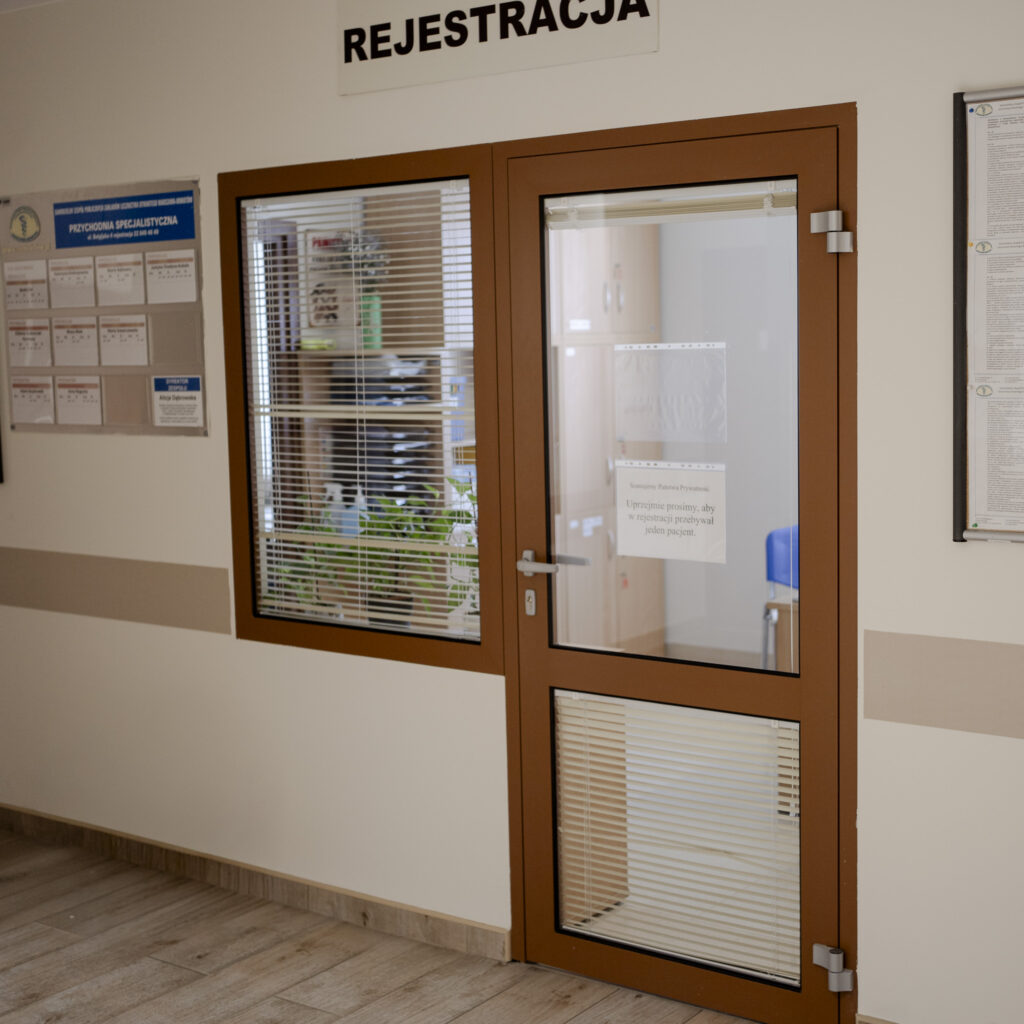 Okienko rejestracji w przychodni z napisem Rejestracja nad drzwiami