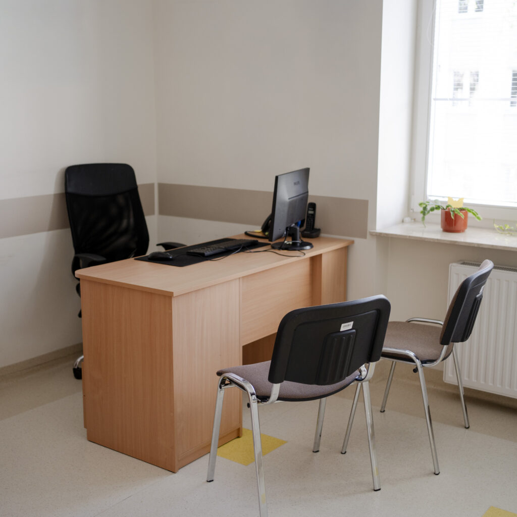 Gabinet lekarski z biurkiem, komputerem i dwoma krzesłami dla pacjentów