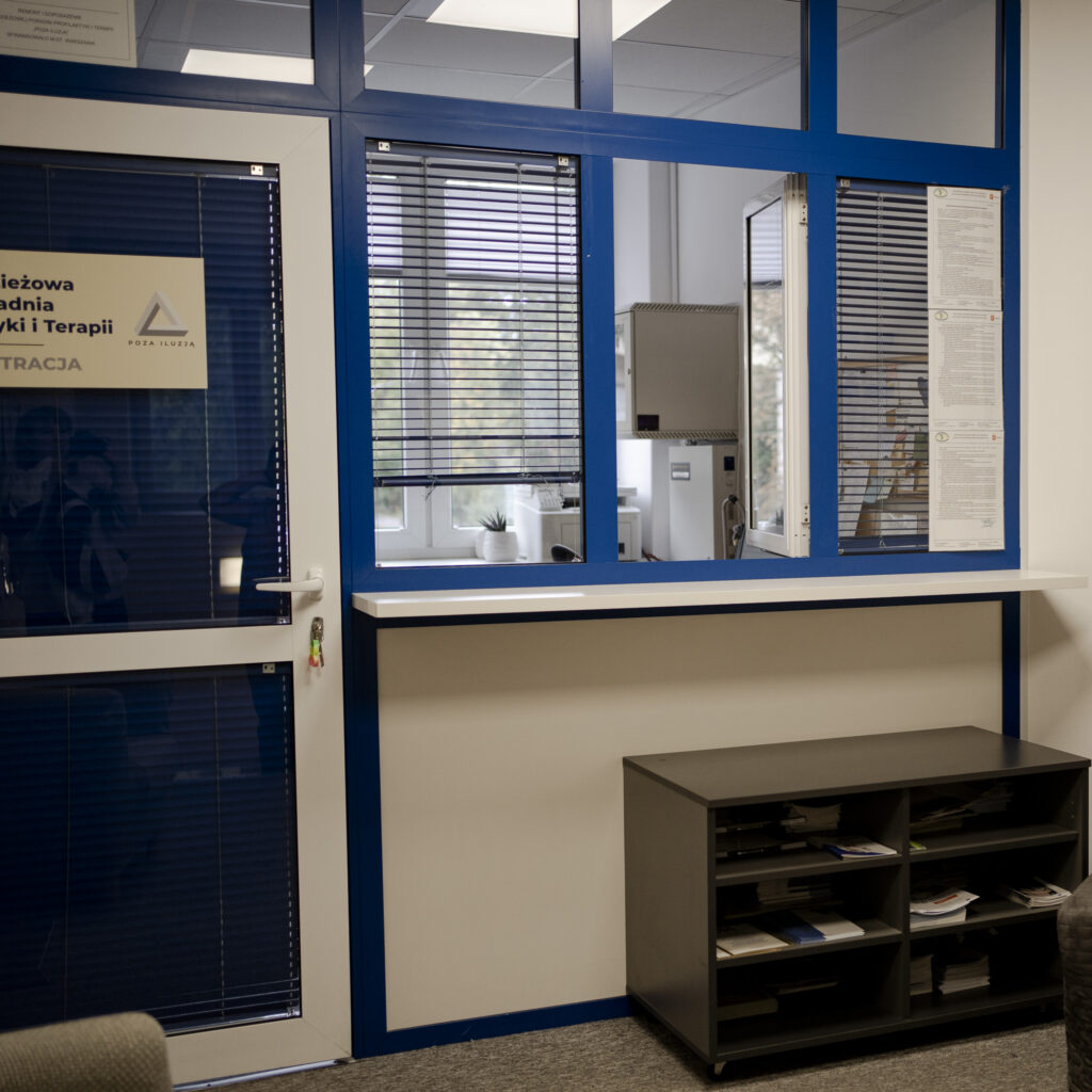 Rejestracja w przychodni z niebiesko-białą ladą i przeszklonym okienkiem