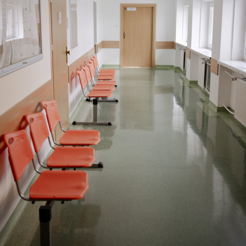 Korytarz przychodni z rzędem pomarańczowych krzeseł dla pacjentów