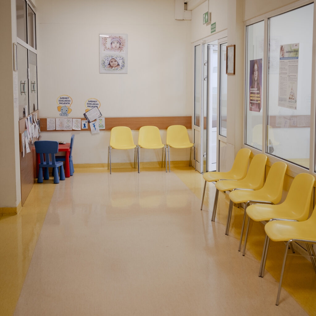 Poczekalnia w przychodni z żółtymi krzesłami i kącikiem zabaw dla dzieci