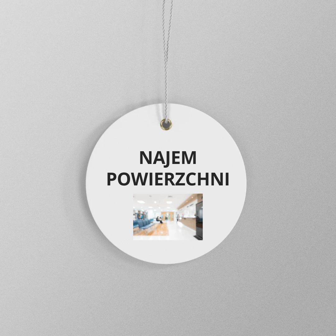 Okrągła zawieszka z napisem NAJEM POWIERZCHNI i małym zdjęciem wnętrza budynku