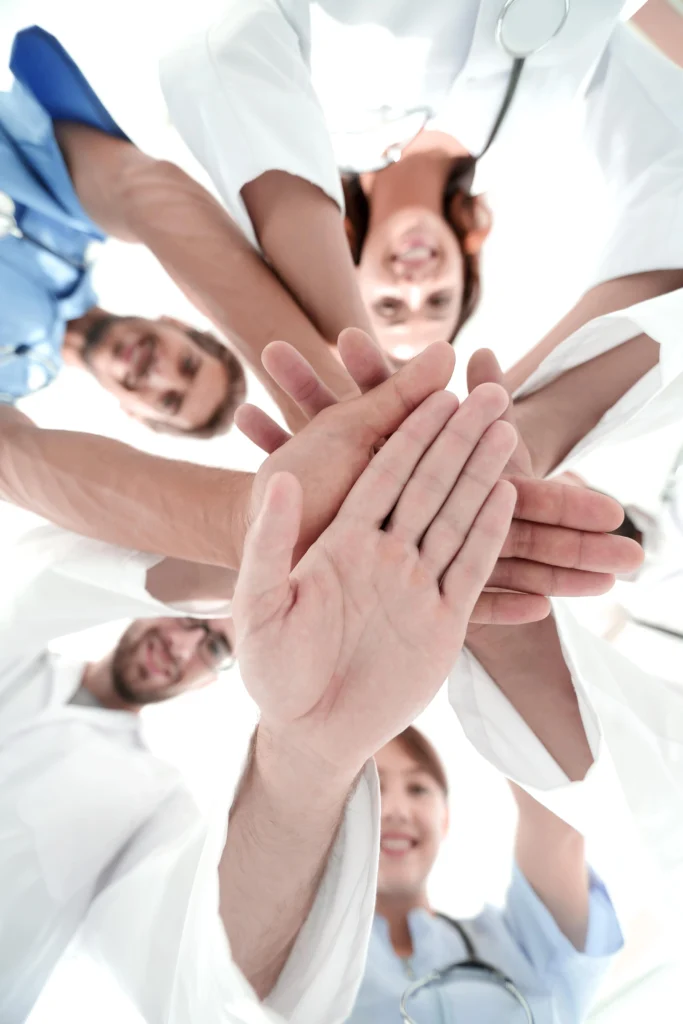 Widok z dołu zespół lekarzy w centrum medycznym splótł ręce razem